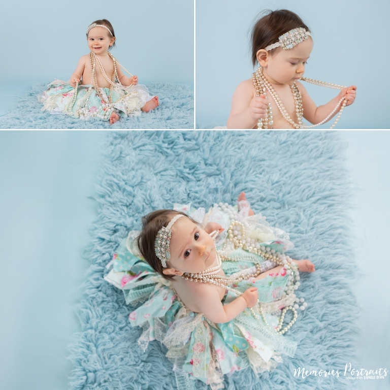 9 month old baby girl in tutu and pearls on blue carpet and background