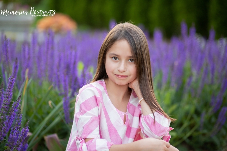 brunette girl in front of purple flowers looking at camera