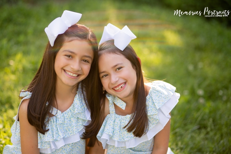 brunette sisters smiling in matching outfits and bows